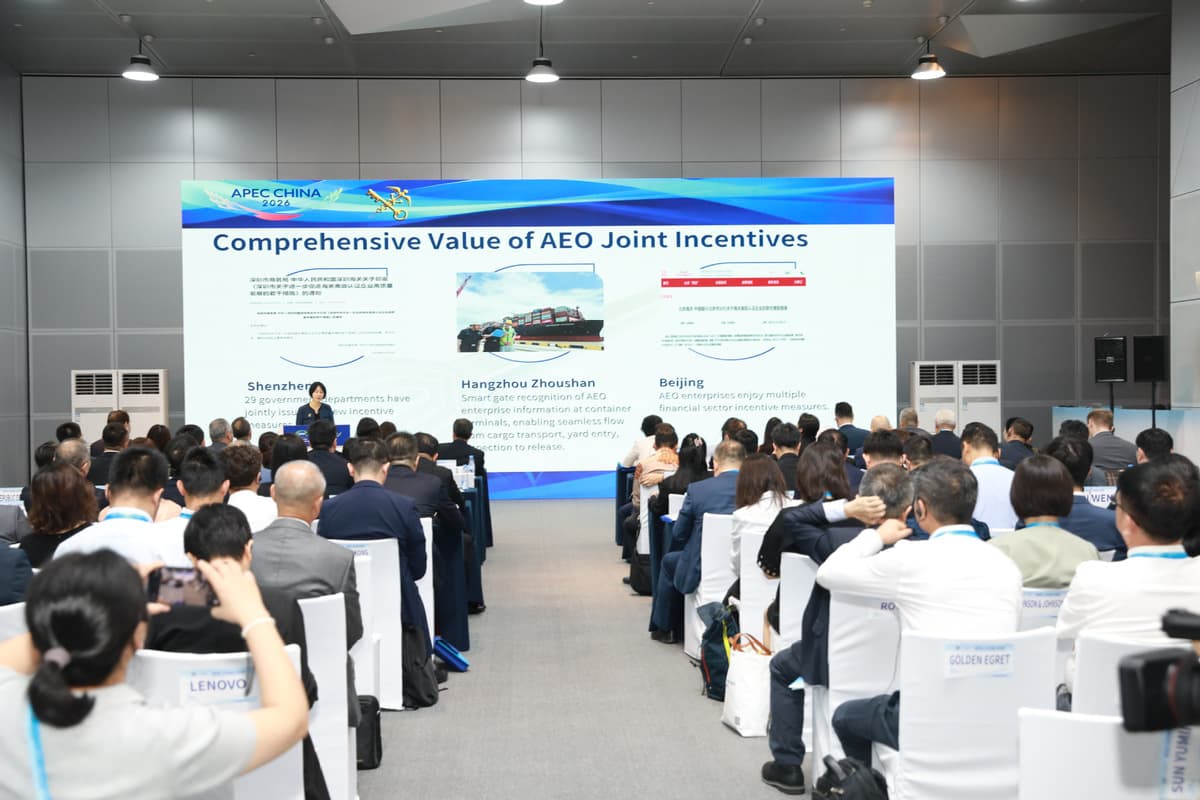 A seminar during APEC China 2026 in Dalian, with a screen showing the comprehensive value of AEO joint incentives and rows of company representatives seated in the audience.