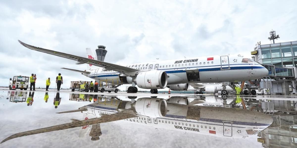 An Air China jet parked at the apron, its fuselage reflected on the rain-soaked tarmac.