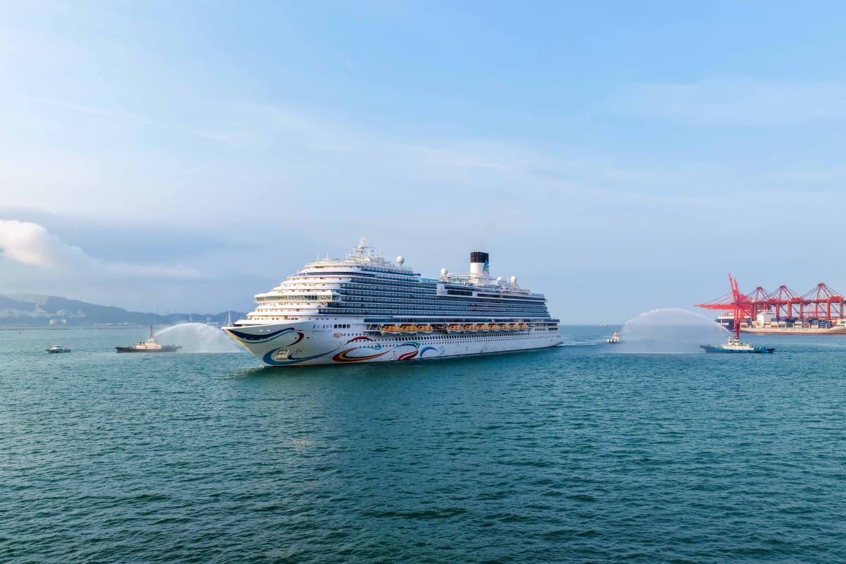 The domestically built cruise ship Adora Magic City leaves port amid a water-cannon salute.