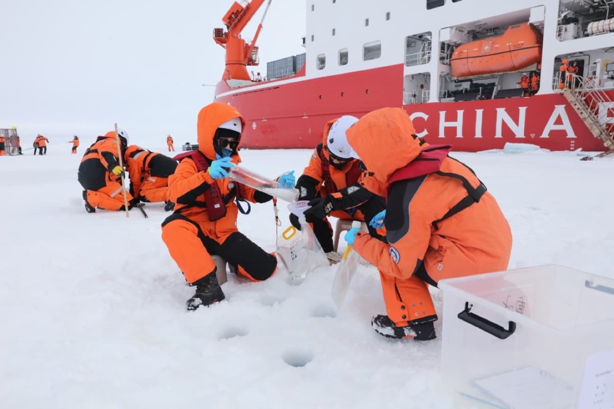 中国科考队员在北冰洋海冰上作业,身后是雪龙号科考船。