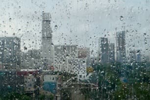 雨水打在玻璃上,城市高楼在雨幕中变得模糊。