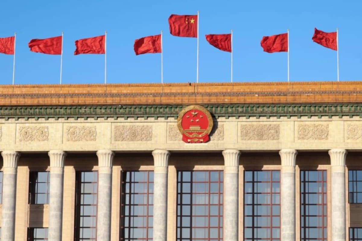 Red flags and the national emblem atop the Great Hall of the People.