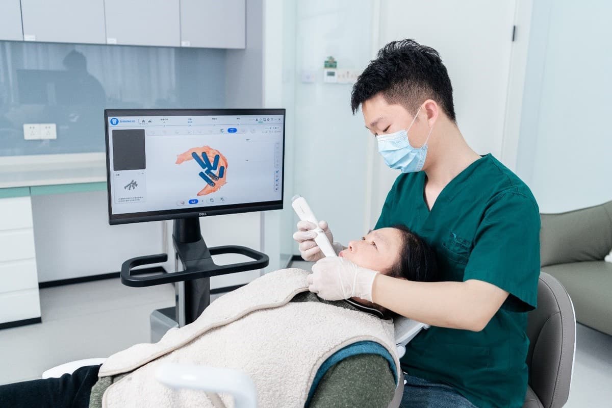 A dentist uses an intraoral 3D scanner on a patient.