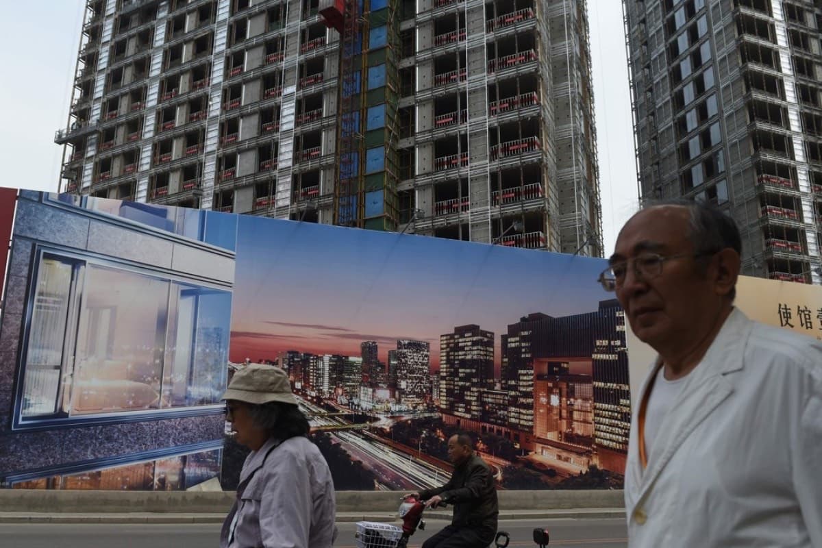 行人经过在建住宅楼前的楼盘效果图围挡