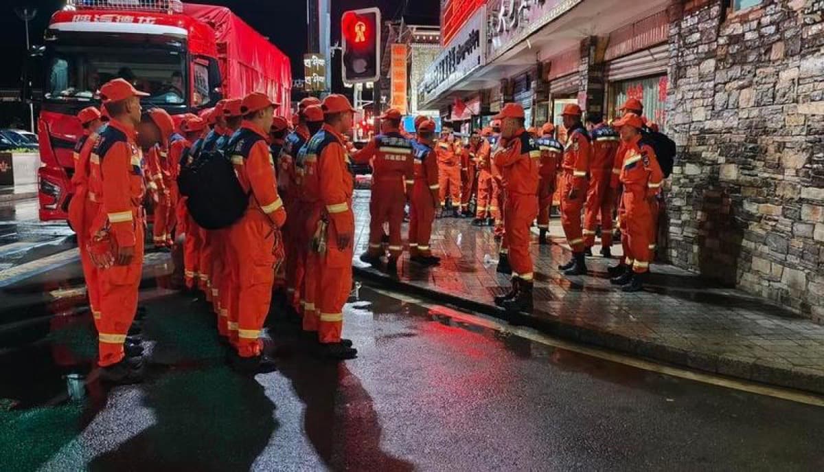 At night, a team of rescuers in orange uniforms gathers on a street near Gyirong port, standing ready before heading into the search and rescue effort.