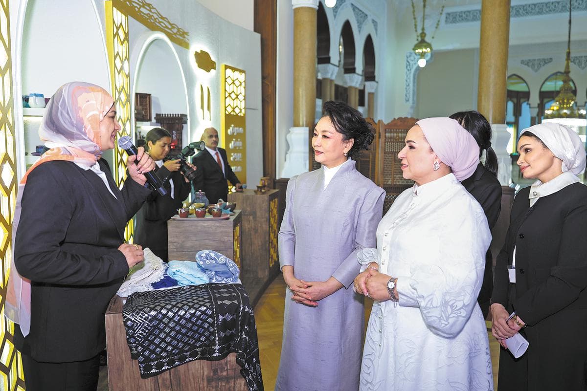 At a handicrafts exhibition in Cairo, Peng Liyuan and Egypt's first lady, Entissar El-Sisi, listen as an artisan describes items on display.
