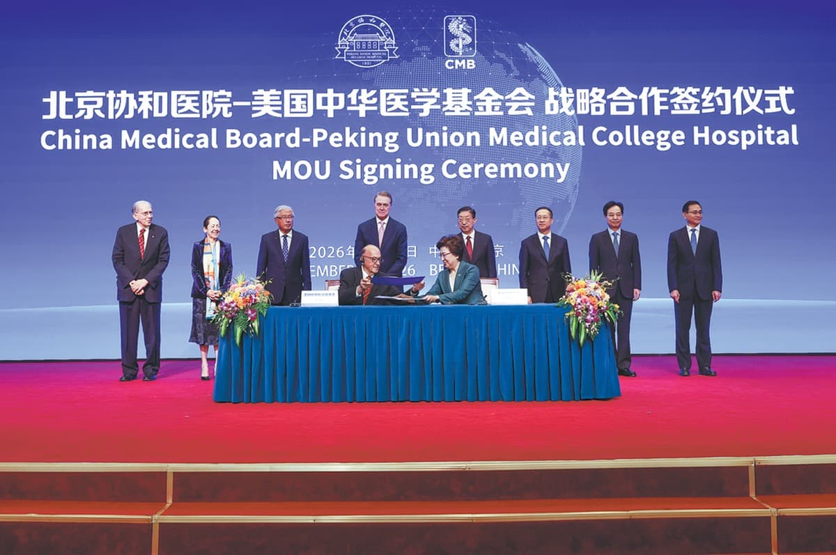 On stage at a signing ceremony in Beijing, Chinese and American representatives sit to sign an agreement, with a screen behind them reading the China Medical Board-Peking Union Medical College Hospital MOU signing ceremony.