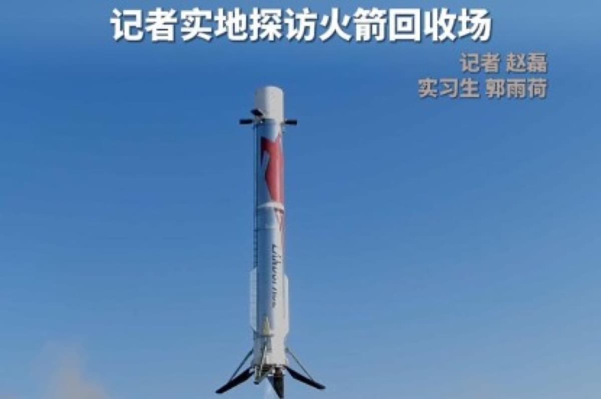 A white and red rocket first stage standing against a blue sky, with Chinese text reading a reporter's on the ground visit to the rocket recovery site.