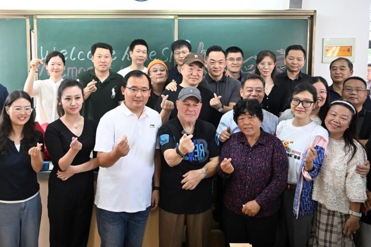 洛阳外国语学校教室内,萨科尔斯基与数十名师生和校友合影,身后黑板上写着欢迎回家的字样。