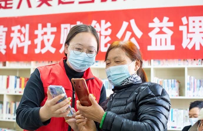 A volunteer helps an older resident use a smartphone at a community centre