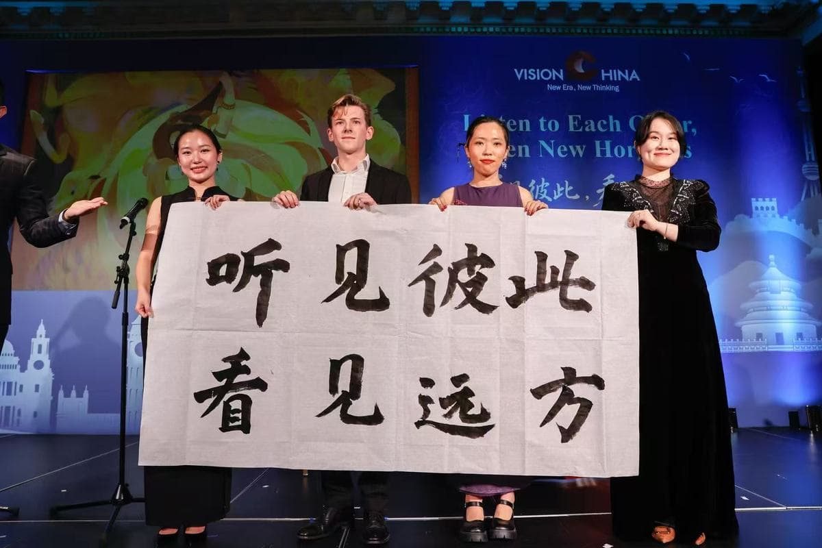 伦敦看中国活动现场,四名中英青年代表共同展示写有听见彼此看见远方字样的书法长卷,背景是活动主题标识。
