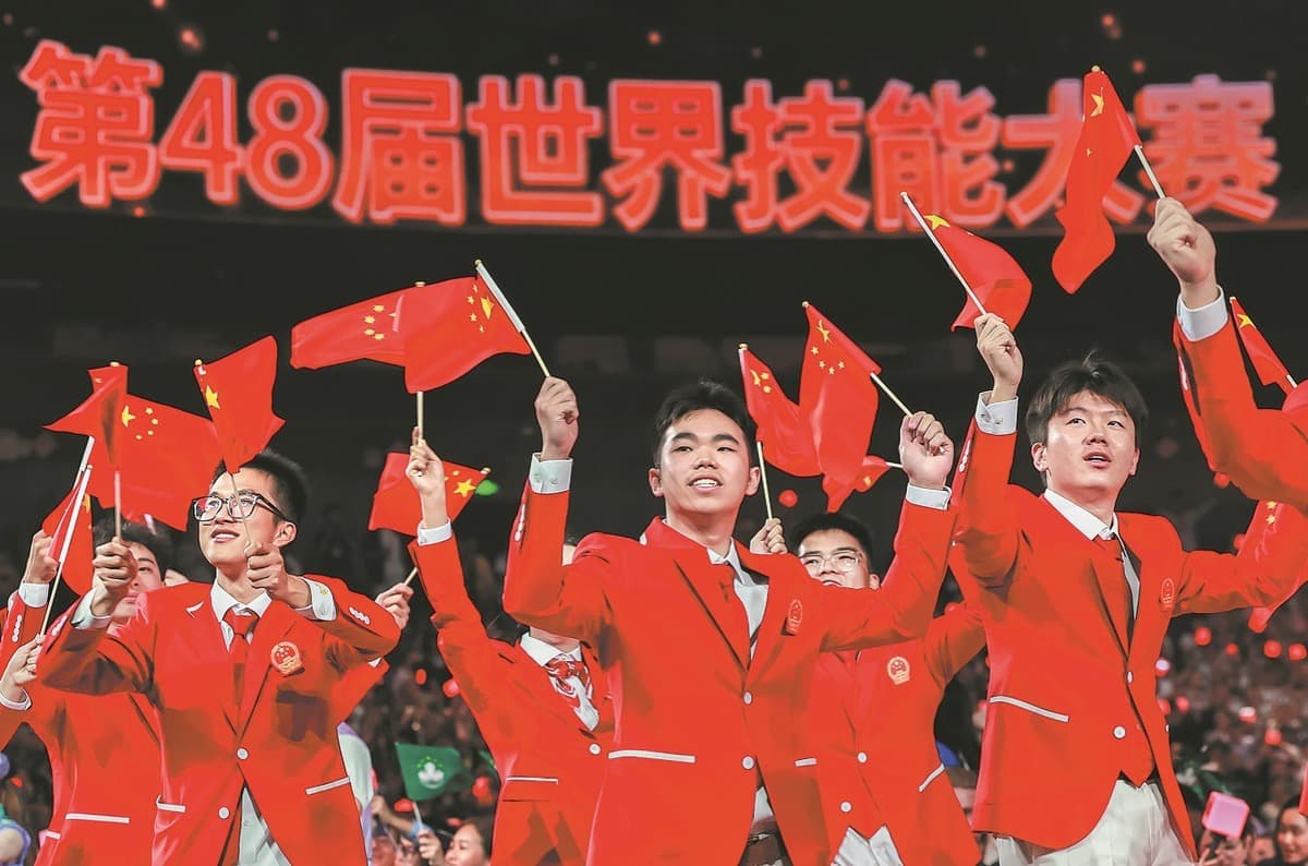 第48届世界技能大赛开幕式现场,多名身穿红色西装的中国代表团成员挥舞国旗,背景大屏幕上显示第48届世界技能大赛字样。