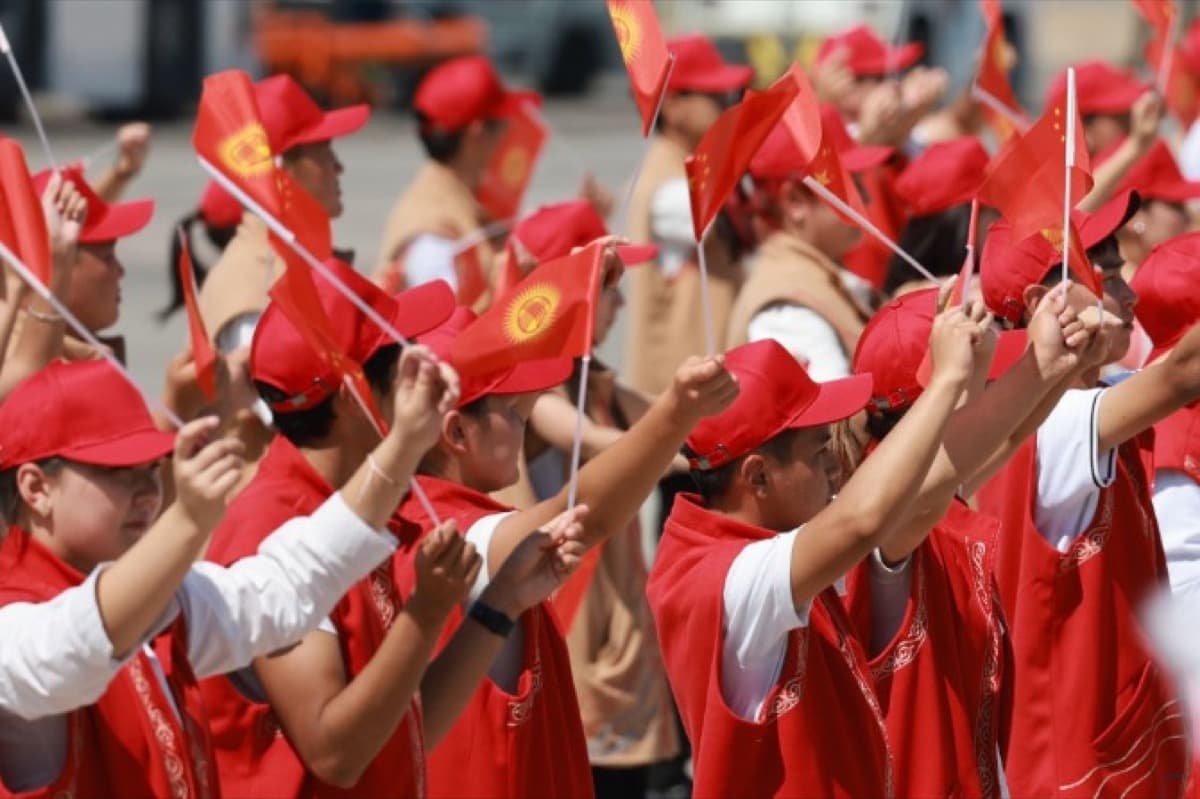 比什凯克街头,身着传统服饰的吉尔吉斯斯坦民众挥舞中吉两国国旗,迎接来访的中国领导人。