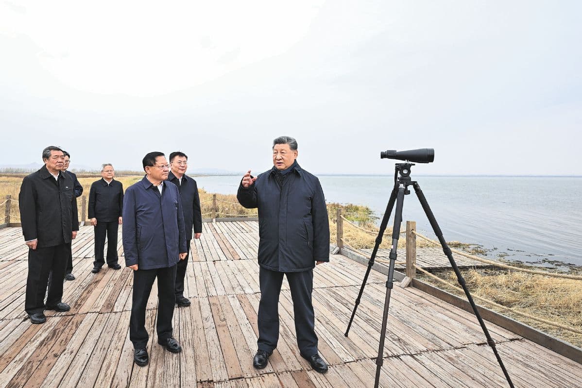 习近平在内蒙古乌兰察布湖畔考察,手指远处水面,身旁多位官员陪同,岸边架设着一台观测用的单筒望远镜。