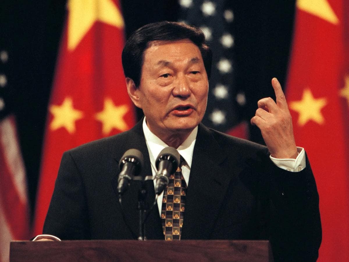 Former Chinese Premier Zhu Rongji speaks at a podium, with Chinese and US flags behind him.